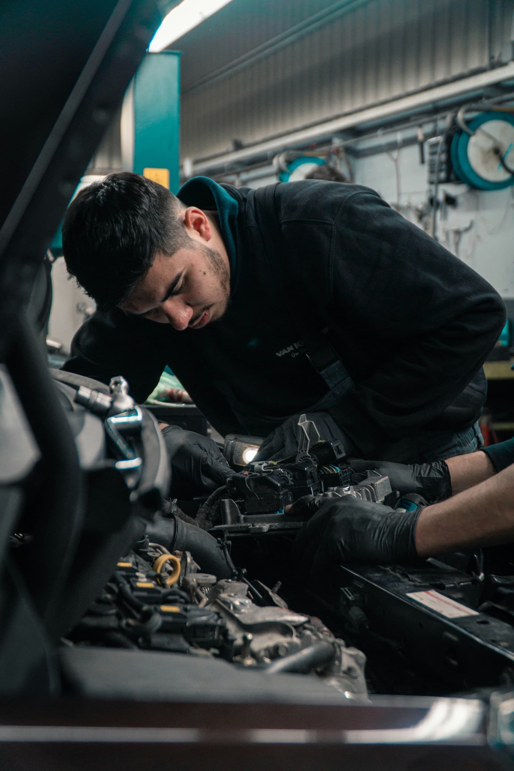 Mechanic in gloves working on a car engine under the bonnet