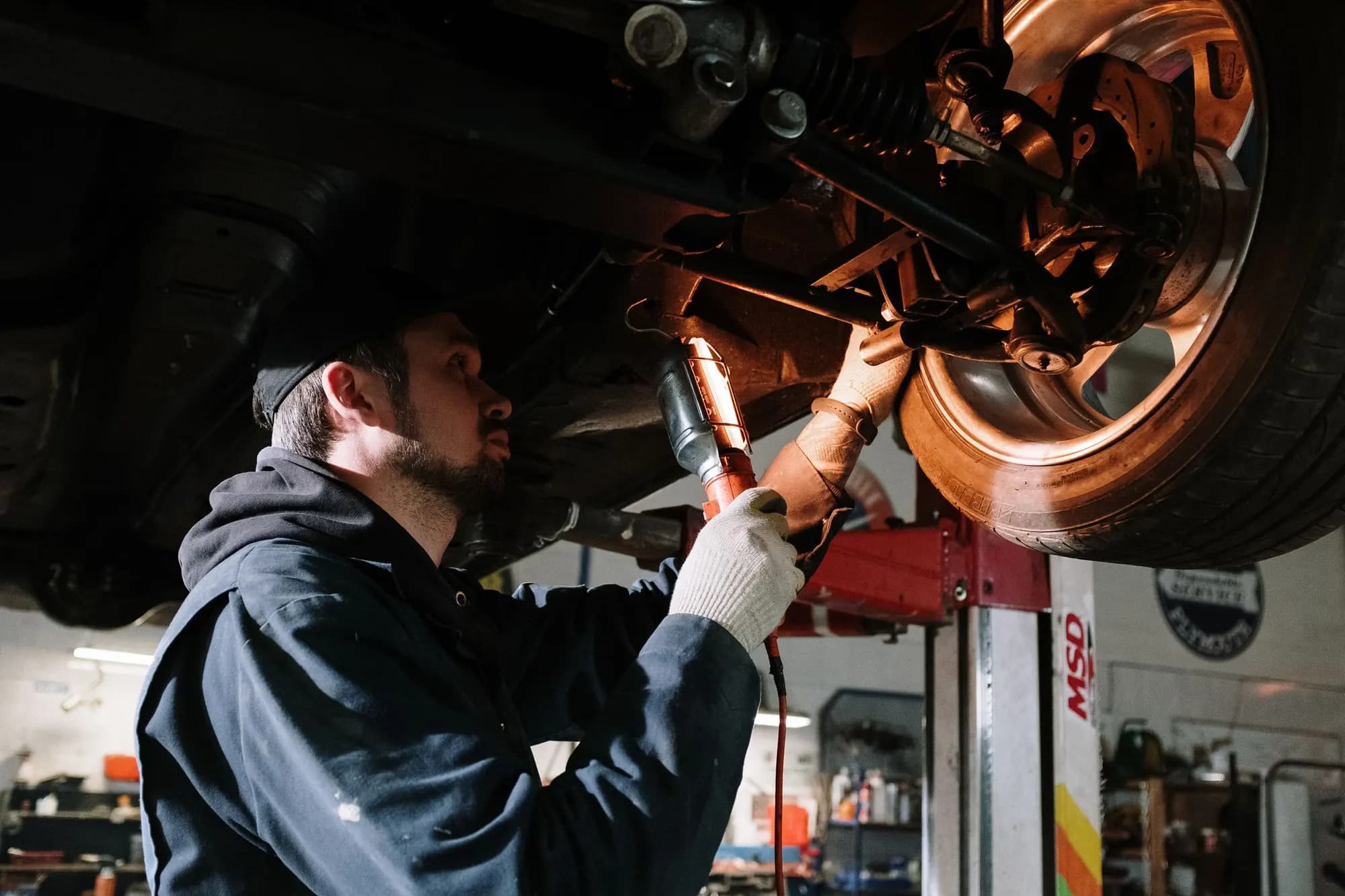A technician working under a vehicle on a two-post hoist