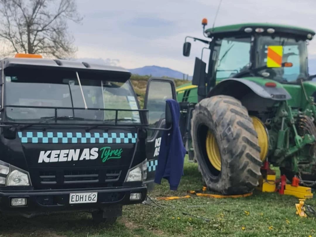 The Keen As Tyres service truck parked beside a tractor in a paddock, the tractor jacked up for a tyre change