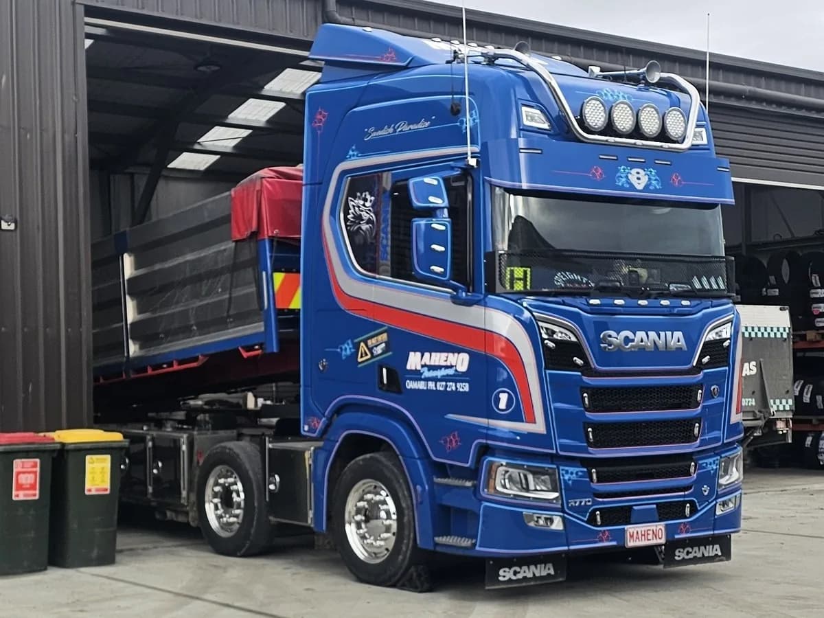 A blue Scania truck parked at the door of a tyre workshop