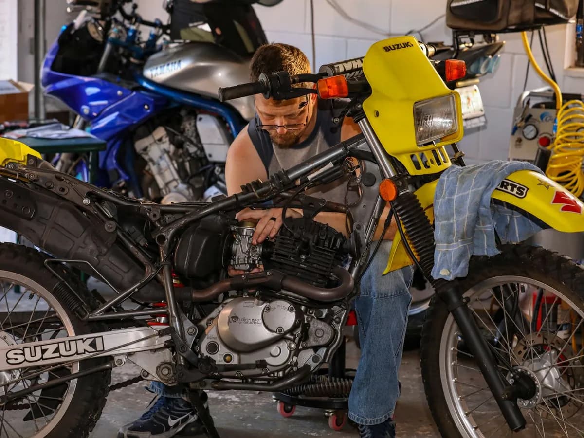 A mechanic working on a trail bike in a home workshop
